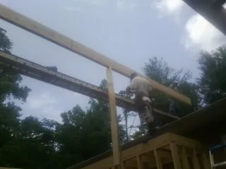 Carpenter setting a ridge beam over a new addition frame — Ice Dam Removal by Roofing Brothers in Surry