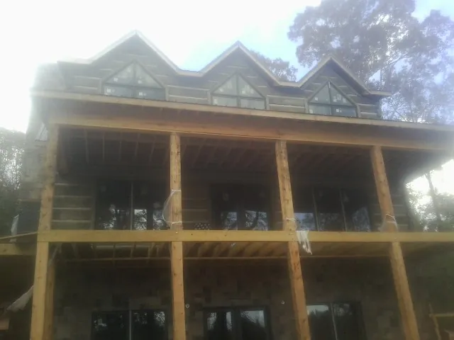 Dormers and porch framing on a large log home under construction — Roof Coating work by our crew in Surry