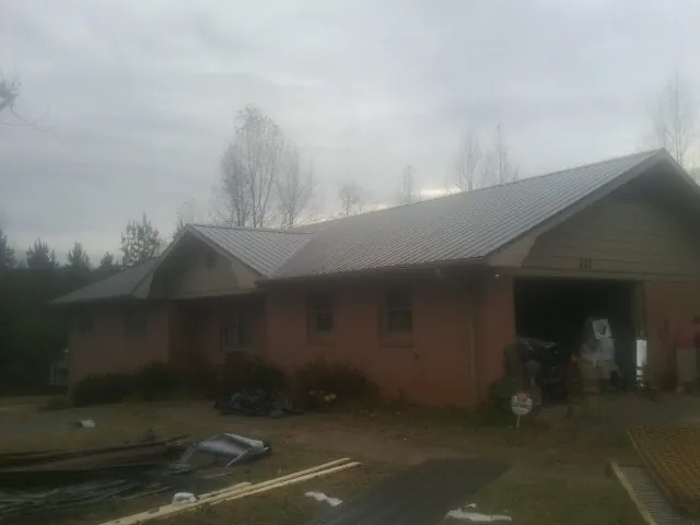 Gray metal roof on a stucco house with an attached garage in Surry