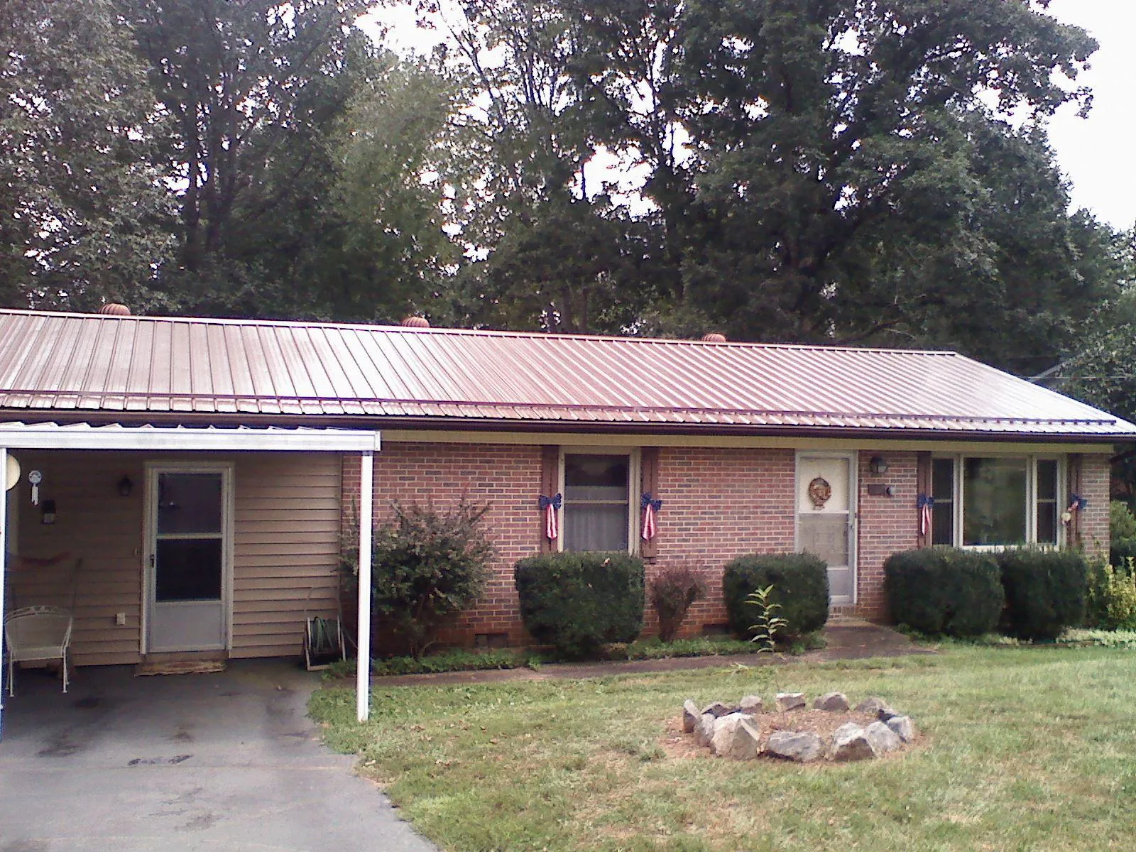 Bronze metal roof and carport on a brick ranch home — Roof Repair work by our crew in Surry
