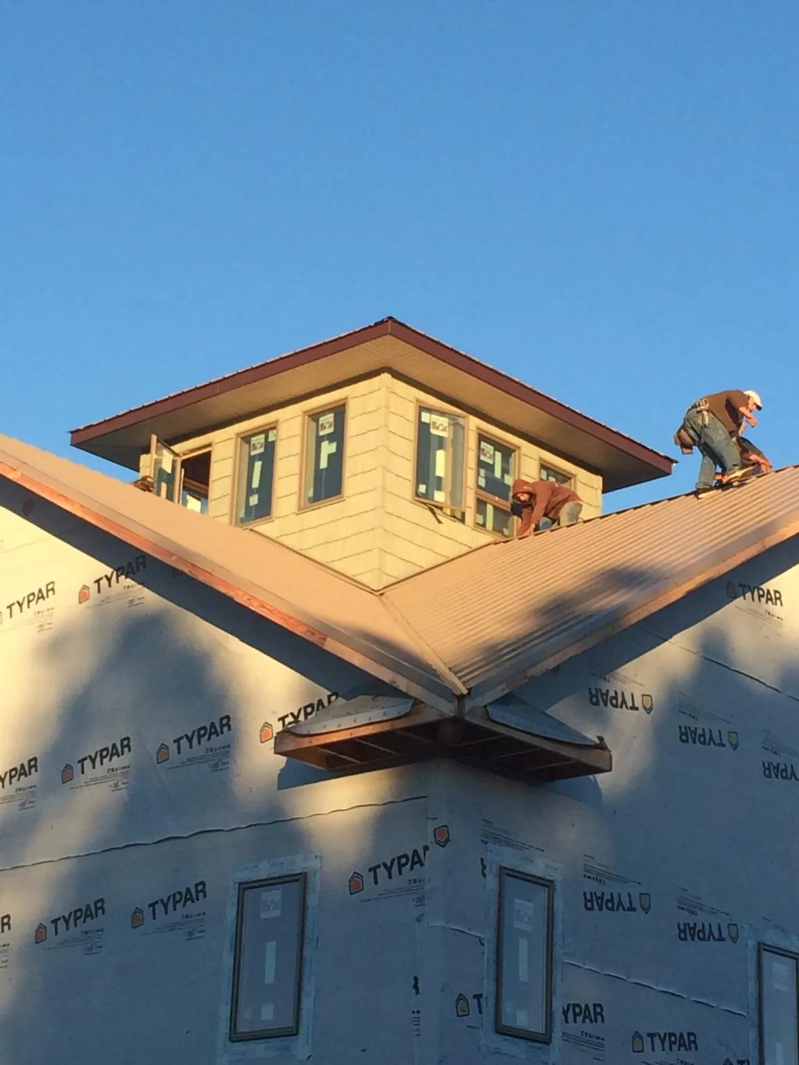 Roofers working around a rooftop cupola on a new metal roof at sunset — Roof Waterproofing in Surry by Roofing Brothers